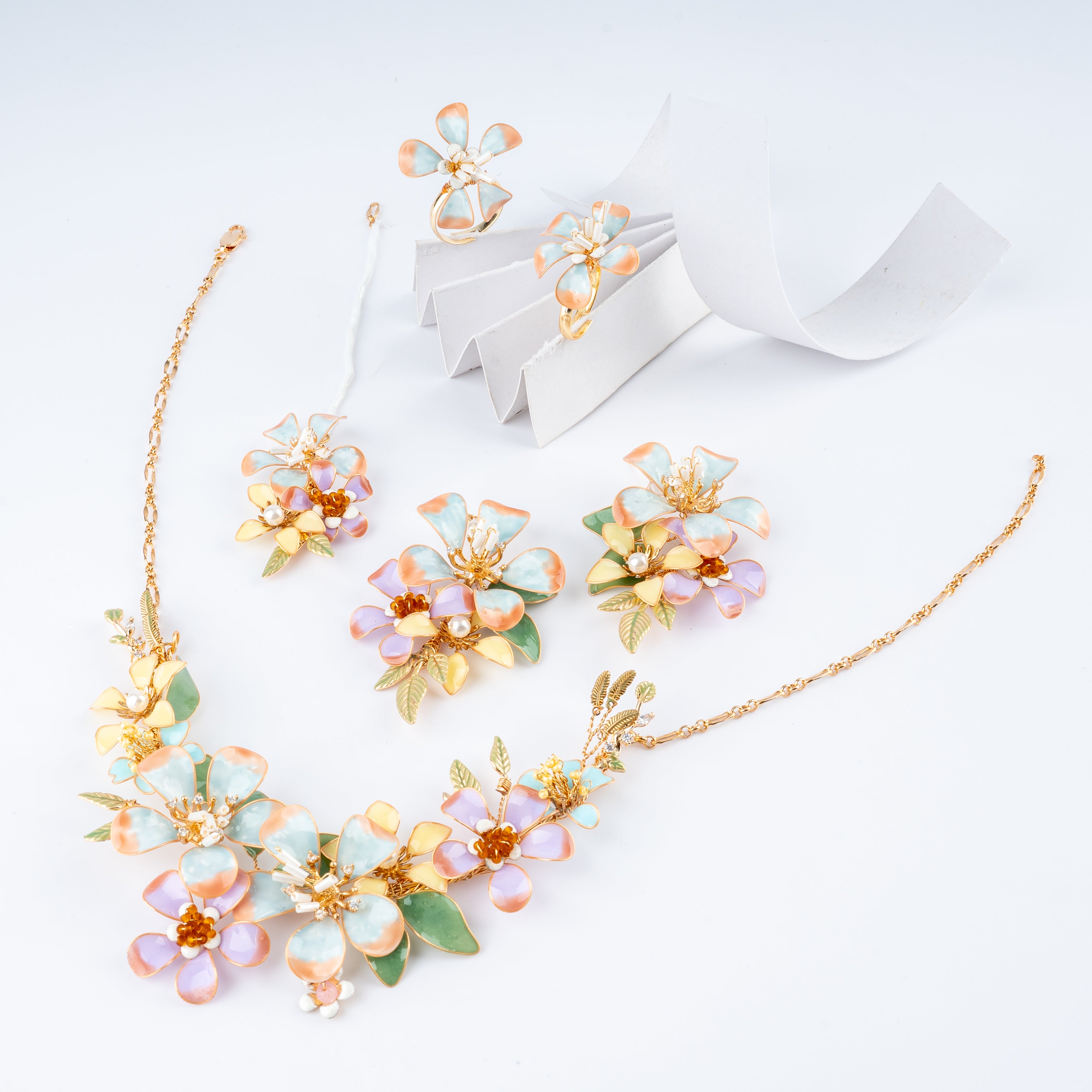 Pastel aqua, peach, and lilac floral resin art jewelry set with necklace, earrings, maang tikka, and rings from US Catalog.   