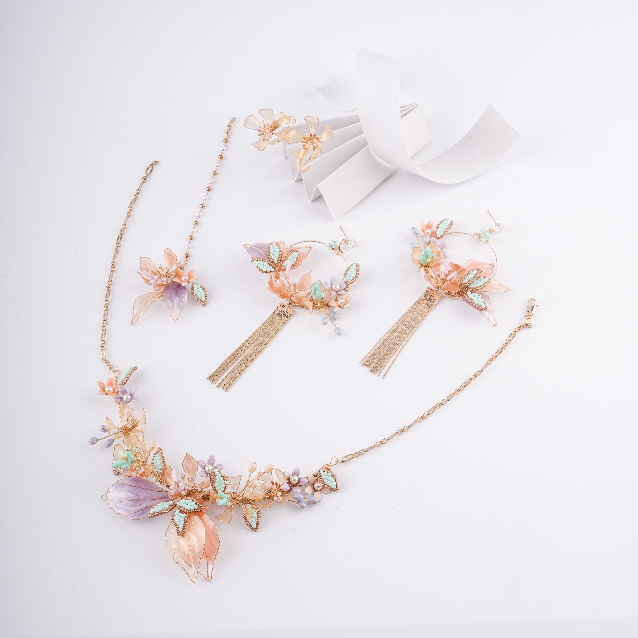 Peach and lilac floral resin art jewelry set with necklace, chain tassel hoop earrings, maang tikka, and rings from US Catalog.   