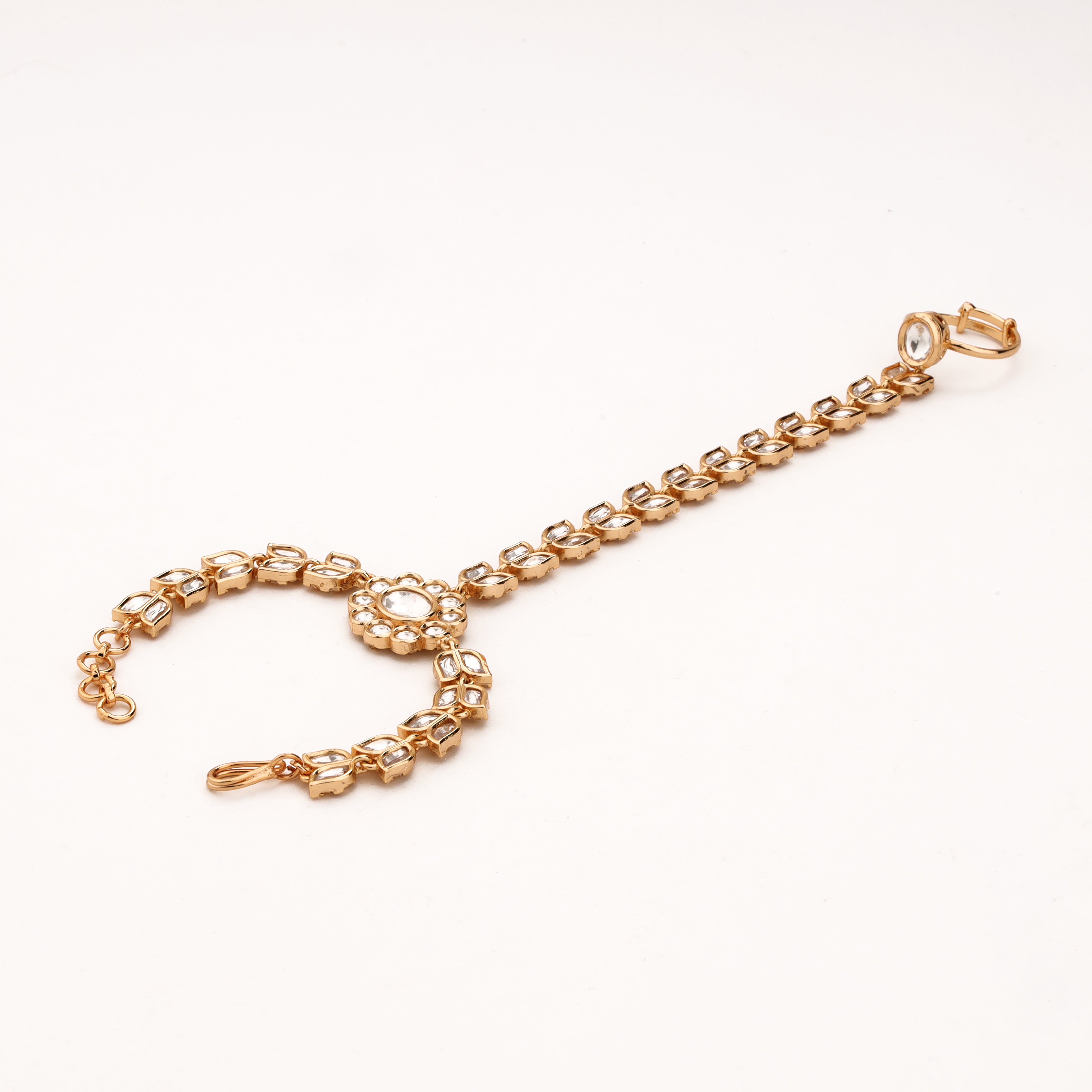 Gold-tone minimal kundan link pocha with clear stones, floral centre, finger ring and adjustable wrist chain
