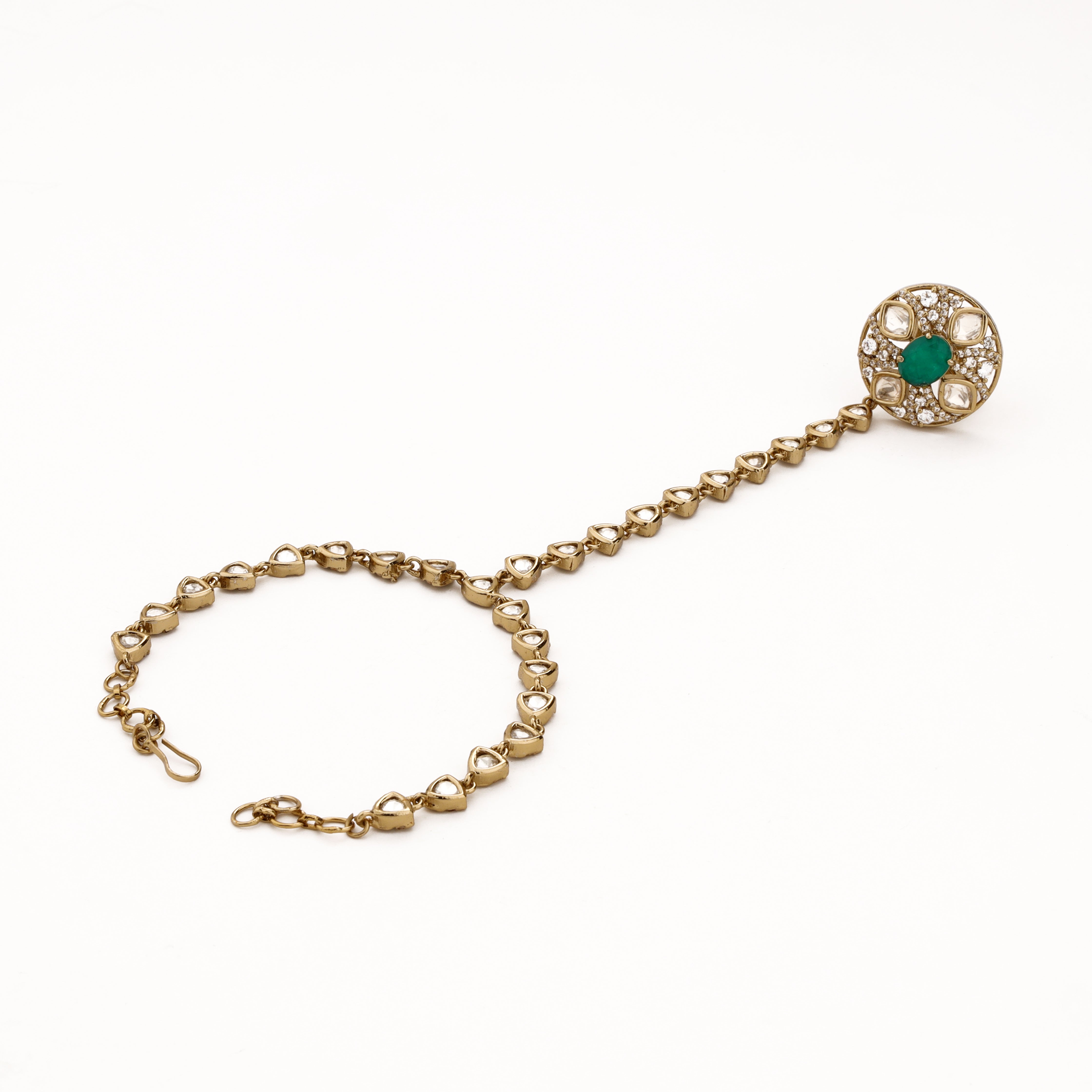Gold-tone kundan pocha with emerald-green centre, white teardrop stone links and adjustable wrist chain