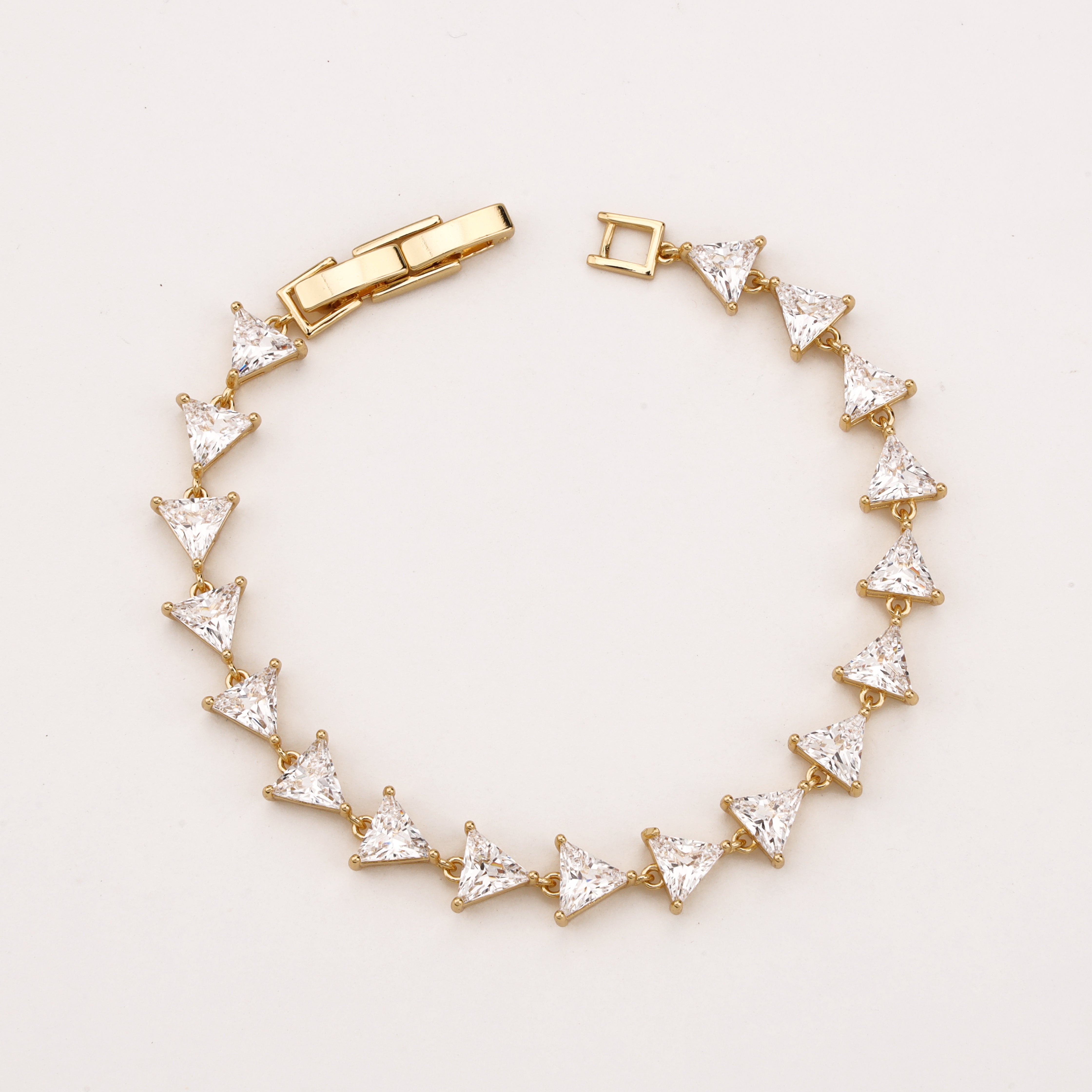 Trielle gold-tone link bracelet with a continuous row of faceted clear triangular crystal stones
