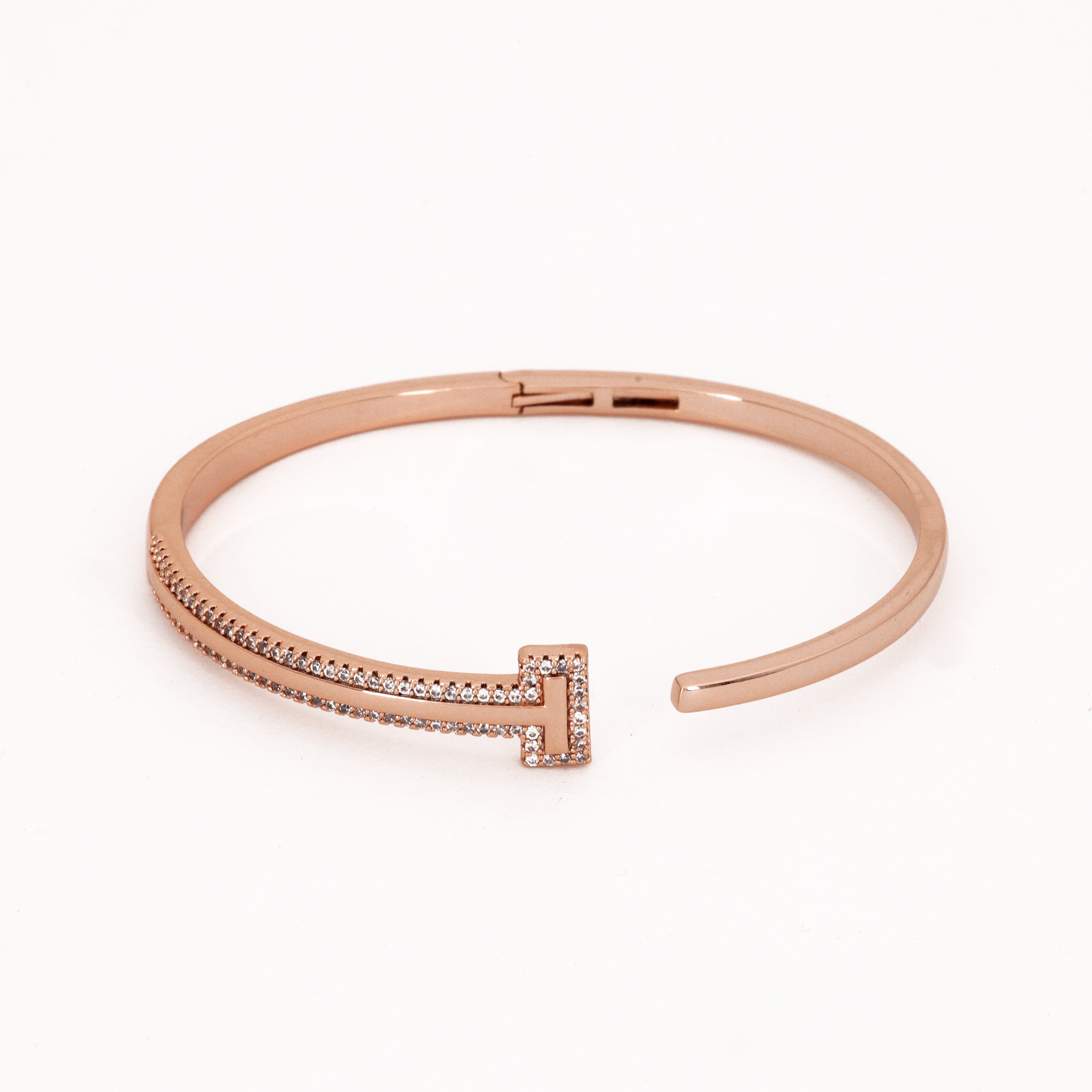 Rose Gold Crystal T-Motif Bangle Bracelet featuring an asymmetrical design with a crystal-encrusted T-bar terminal on a white background