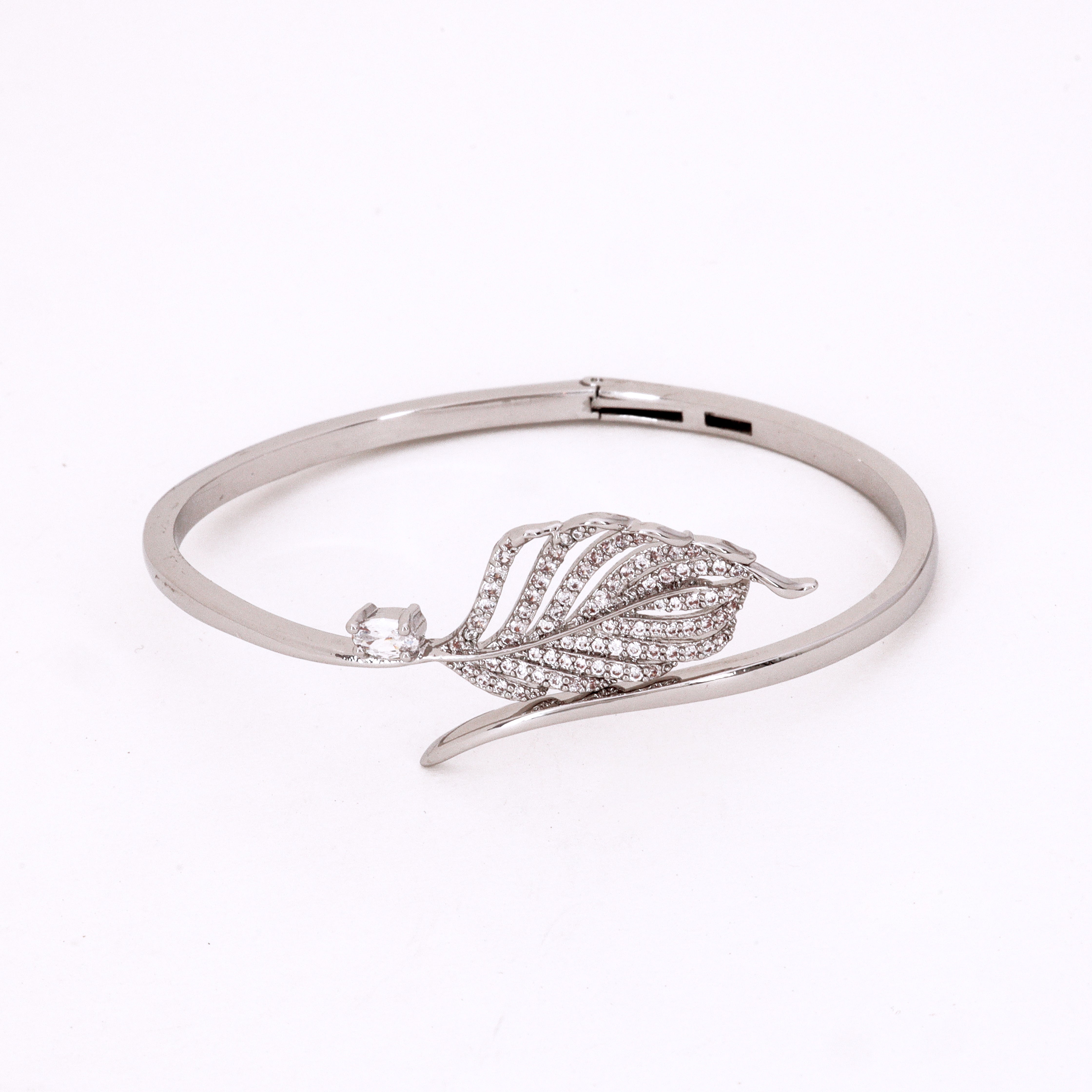 Silver Tone Crystal Feather Bypass Bracelet featuring an intricate pavé crystal feather motif and a smooth wrap-around band on a white background for US Catalog.
