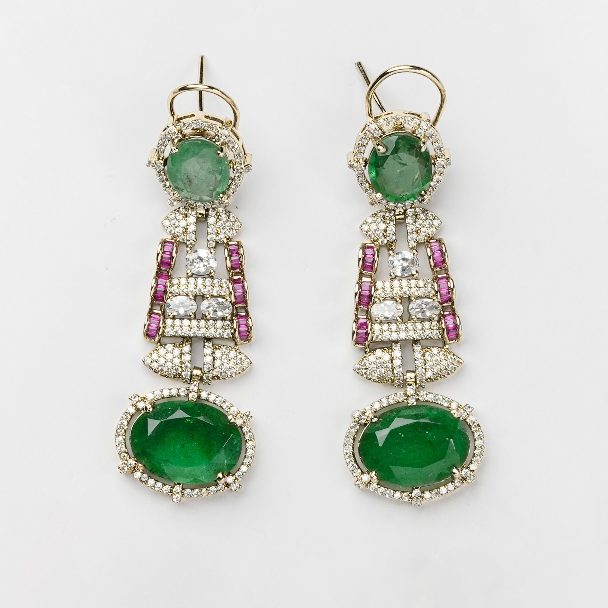 A pair of gold dangle earrings featuring oval green emerald-cut gemstones, surrounded by pavé-set clear stones and accented with pink cubic zirconia, shown on a plain white background.