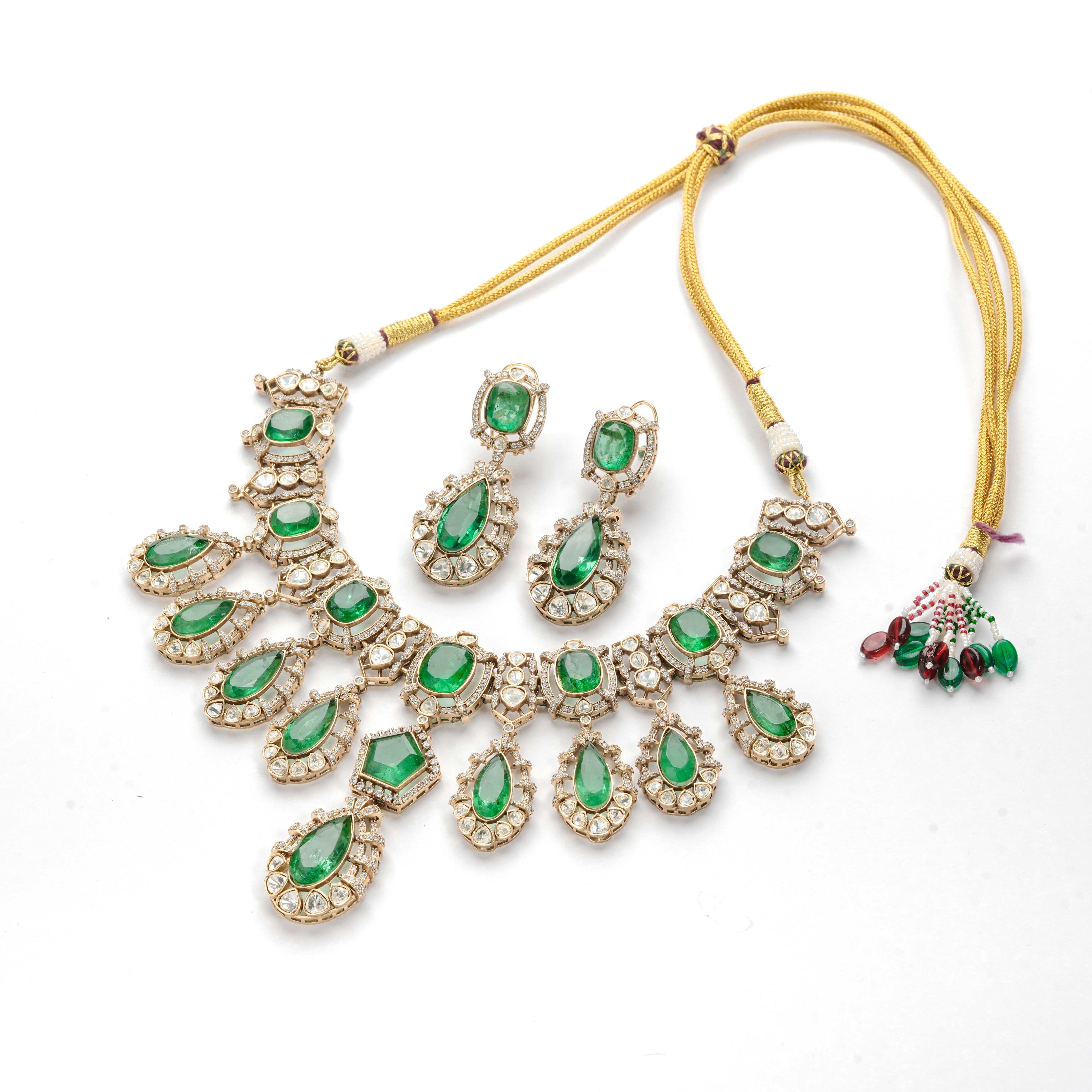 Antique gold finish green stone kundan polki necklace set with teardrop drops and matching drop earrings for bridal wear.