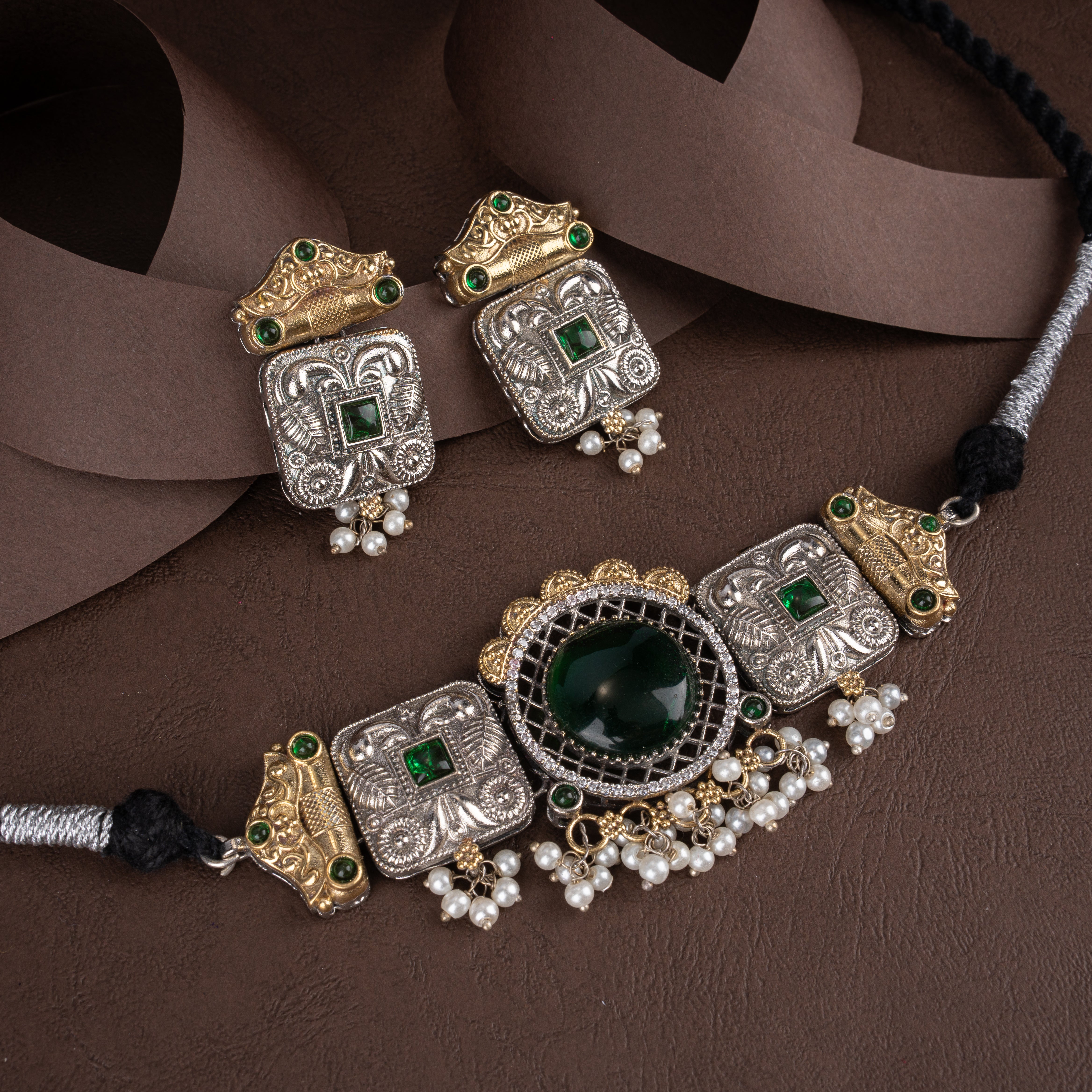 Dual-tone oxidised silver and antique gold choker necklace set featuring a round cabochon centerpiece, square-cut accent stones, pearl drops, and matching earrings.