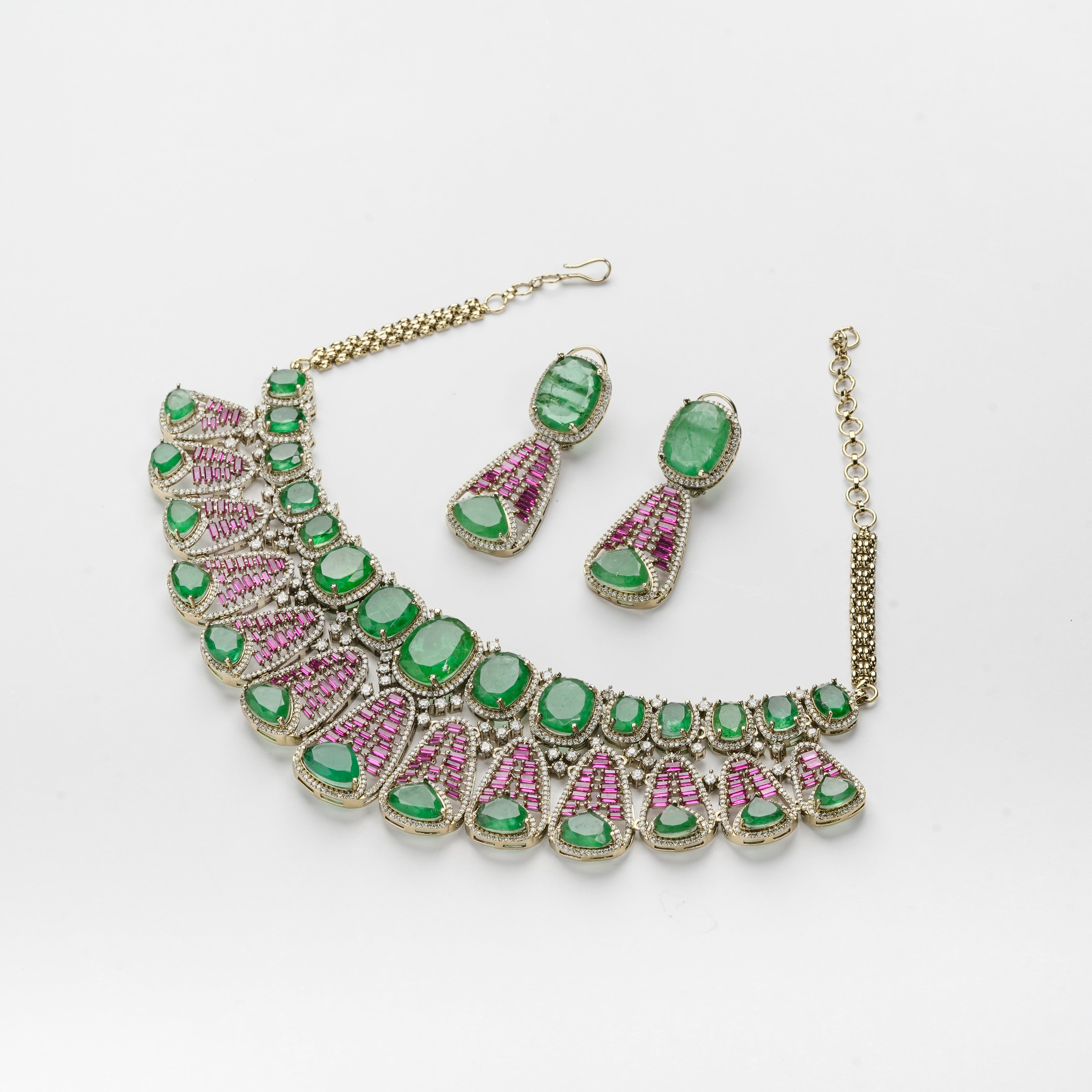Gold-tone jewelry set featuring a statement collar necklace and matching drop earrings, embellished with green cabochon stones and pink pavé accents, displayed on a clean white background.